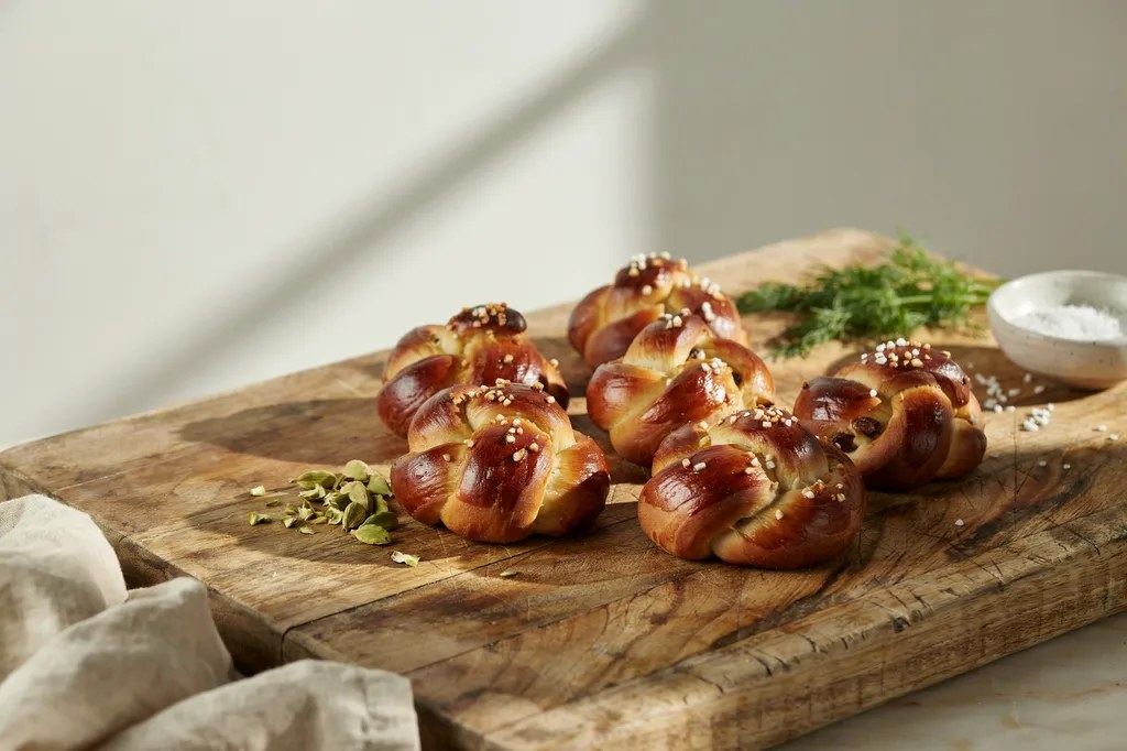 Knotted Scandinavian cardamom buns, burnished and glossy with syrup glaze and scattered with pearl sugar.
