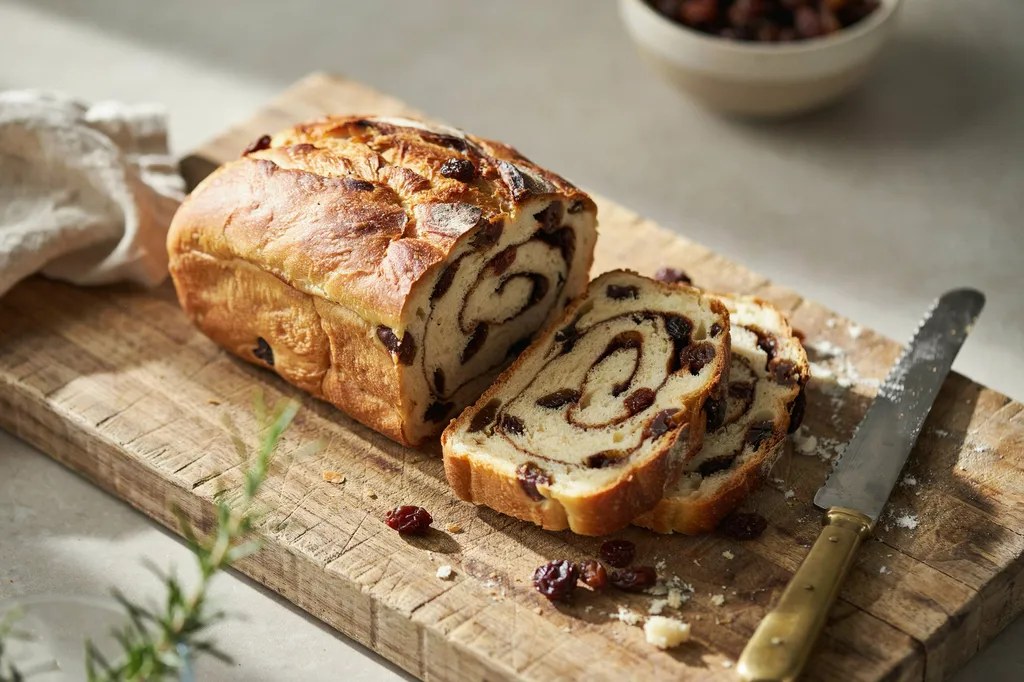Slices of whole grain bread each showing a bold cinnamon spiral and plump raisins through the crumb.